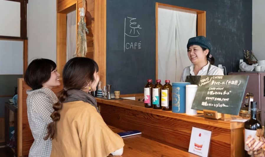 カウンター越しに笑顔で会話する女性店員と二人の女性客