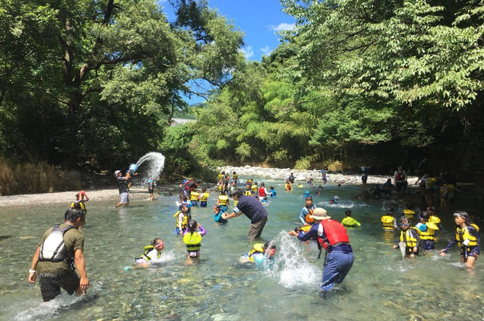 水が澄んだ浅い川で遊ぶ子供たち