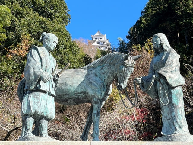 男女の銅像と奥に見える城